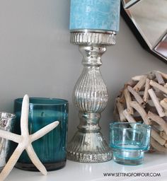 some candles are sitting on a mantle with starfish decorations around them and one candle is blue