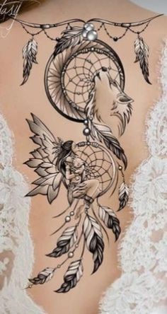 the back of a woman's body with tattoos and feathers on her shoulder,