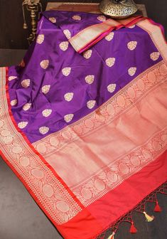 This Saree speaks of the rich design traditions of Banaras. It is set in a sought-after color combination. The rich body of the saree set in purple color features delicately woven Damask motifs in zari. This is complimented perfectly by the grand pallu and borders set in red color.The base material used to craft the saree is buttery soft katan silk. The motifs are woven in zari by employing the meticulous kadhuwa technique. In this style of weaving, motifs are individually woven into the saree l Damask Motifs, Banarasi Katan Silk Saree, Rich Design, Katan Silk Saree, Chanderi Silk Saree, Eyelet Blouse, Katan Silk, Zari Work, Beautiful Color Combinations