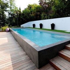 an empty swimming pool in the middle of a wooden decked area with steps leading up to it