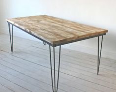 a wooden table sitting on top of a hard wood floor next to a white wall