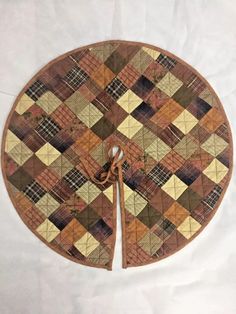 a round wooden cutting board covered in brown and tan plaid fabric with two scissors on each side