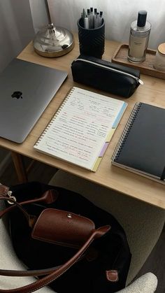 a desk with a laptop, notebook and other items on it