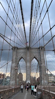 people walking across the brooklyn bridge on a cloudy day