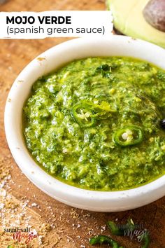 a white bowl filled with green sauce next to an avocado