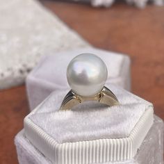 Two-tone 14KT white gold + yellow gold band ring with genuine, cultured Paspaley South Sea Pearl. Choose your finger size Contact us for additional sizes 12mm Paspaley Pearl; "Fine" quality; "Circle" shape Paspaley Certificate of Authenticity included Weight: 6.31g Made to order: please allow 7-10 business days prior to shipping Pearl will vary slightly from photos Classic White Oval Dome Ring, White Dome Ring With Polished Finish For Anniversary, Timeless White Pearl Ring, Classic White Dome Ring For Wedding, Anniversary White Dome Ring With Polished Finish, White Pearl Ring With 14k Gold Round Band, White Pearl Ring With Round Band, Fine Jewelry White Pearl Ring With Round Band, White 14k Gold Round Ring