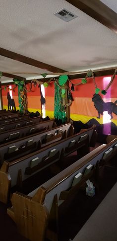 an empty church filled with pews covered in paper mache animals and trees on the wall