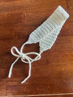 a crocheted hat tied up on top of a wooden table