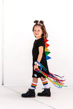 "Rainbow dinosaur spike girls twirly dress will be a favorite with your little fashion toddler girl. Kids dinosaur dress makes a sweet birthday gift or St Paddy's outfit for the little one on your list. Handcrafted spikes are sewn on to create a dino dressup costume they'll love. Our twirly skirt dinosaur dress is fun for pretend play and equally matched for hanging out. Dinosaur spike dress has short sleeves and is made with a black pleated Rabbit Skins dress with felt spikes stitched down the Multicolor Ruffle Twirl Dress For Playdate, Playful Ruffle Twirl Dress For Playwear, Playful Ruffled Twirl Dress For Playwear, Multicolor Ruffled Twirl Dress For Playdate, Playful Rainbow Dress With Ruffles, Playful Short Sleeve Twirl Dress, Cute Rainbow Dresses With Ruffles, Cute Rainbow Ruffled Dresses, Playful Short Sleeve Twirl Dress For Playdate