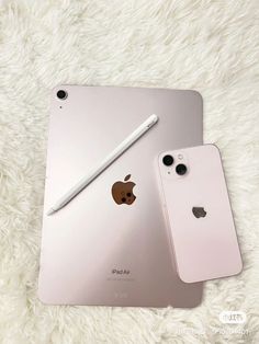 an apple ipad next to another one on a fluffy white surface with a pen in the middle