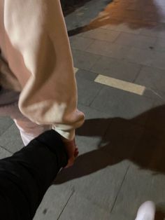 two people walking down the street holding hands and touching each other's feet with their shadows on the ground