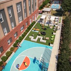 an aerial view of a basketball court in the middle of a courtyard with picnic tables and lounge chairs