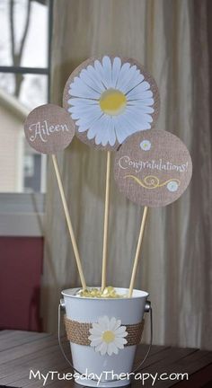 there are three flowers in a bucket with some stickers on it that say congratulations