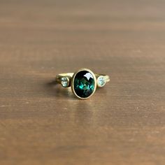 A bewitching teal tourmaline is elegantly positioned between a pair of beryls in this dazzling ring. 14k green gold Tourmaline 7mm x 9mm (1/4" x 3/8")Beryls 3mm (1/8") in diameterSapphires 1mm in diameter Oval Tourmaline Emerald Ring With Bezel Setting, Oval Tourmaline Ring For May Birthstone, Tourmaline Ring With Center Stone For May Birthstone, May Birthstone Ring With Center Stone Tourmaline, Jewelry Making Classes, Newport Ri, Aqua Marine, Three Stone Rings, Three Stone