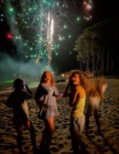 three girls standing on the beach with fireworks in the background