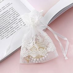 an open book with white lace on it and a bag filled with pearls in the middle