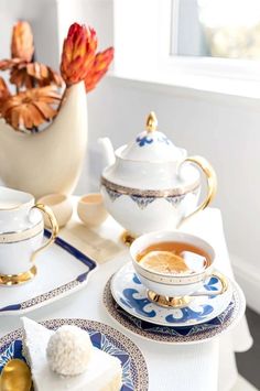 a table topped with blue and white plates covered in dessert next to a potted plant