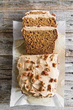 two slices of carrot bread with frosting and nuts on top sitting on napkins