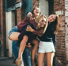 four young women are hugging and laughing on the street