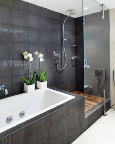 a bathroom with a tub, shower head and flowers in vases on the counter