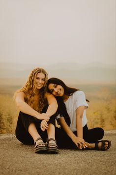 two women sitting on the ground with their arms around each other