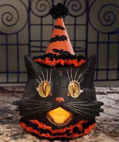 a black cat wearing a witches hat on top of a table with orange and black decorations