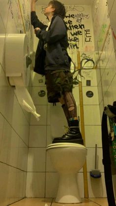 a man standing on top of a toilet in a bathroom