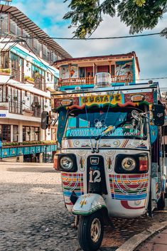 a colorfully painted bus parked on the side of the road in front of some buildings