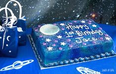 a blue birthday cake sitting on top of a table covered in stars and moon decorations