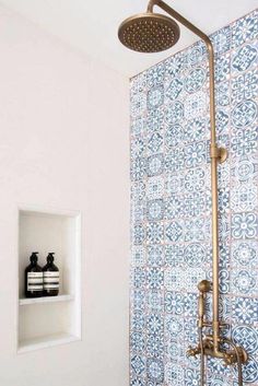 the shower head is mounted on the wall above the toilet in this bathroom with blue and white tile