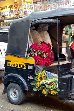 a tuk - tuk loaded with flowers is parked on the street