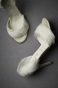 two pairs of white shoes with feathers on the bottom and one pair of high heeled shoes