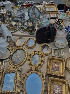 a table topped with lots of framed pictures and mirrors