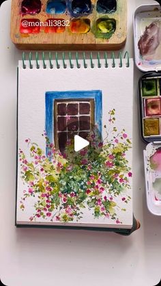 an open book with watercolors and paint on it