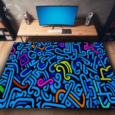 a computer desk with a colorful rug on the floor next to a monitor and speakers