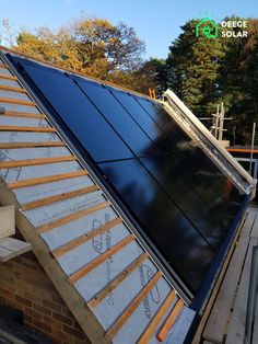 a solar panel on the roof of a house being built with wood and metal shingles