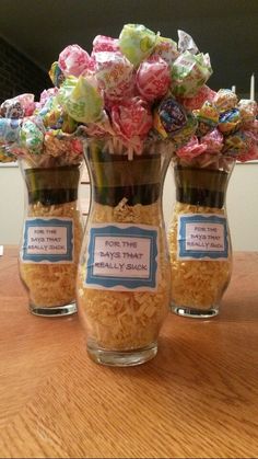 three glass vases filled with candies on top of a wooden table