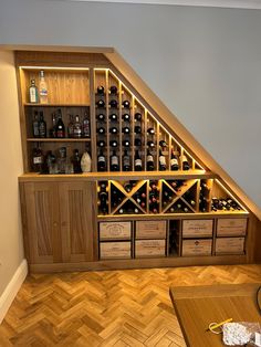 a wine cellar in the corner of a room under a slanted wall with shelves and drawers