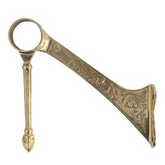 an ornate gold colored metal object with a long handle and decorative design on the side