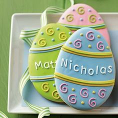 three decorated cookies on a plate with the words nicholas written in large, small letters