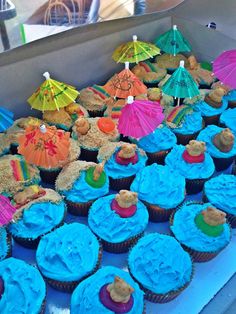 there are many cupcakes with blue frosting and beach umbrellas on them