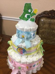 a multi layer diaper cake sitting on top of a wooden table next to a teddy bear