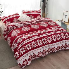 a red and white bed with snowflakes on it in front of a window