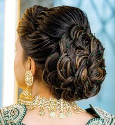 a woman with long hair and green beads on her neck is looking at herself in the mirror