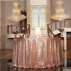 a table with a gold sequined cloth on it and chandeliers hanging from the ceiling