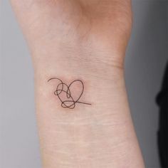 a small tattoo on the wrist of a woman's left arm, with an intertwined heart