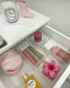 an open drawer filled with cosmetics and personal care items on top of a white table