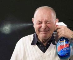 an older man holding a bottle of mouthwash in his right hand and smiling at the camera