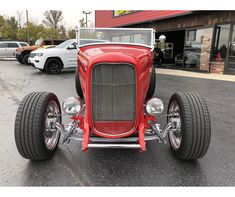 an antique red car parked in front of a building