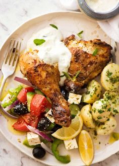 a white plate topped with chicken, potatoes and veggies next to a fork